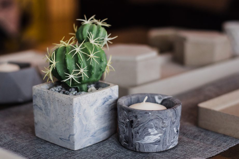 Ang's designs can function as a plant pot or candle holder. Concrete and Vines.