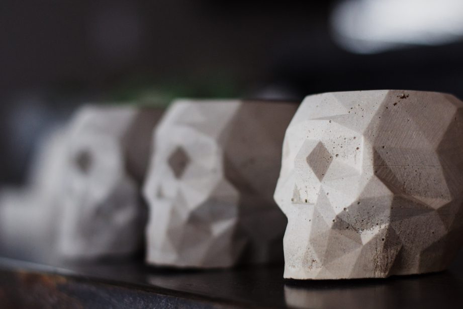 A row of concrete skull plant pots on a table.