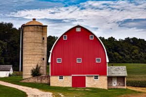 A tall silo next to a red barn.