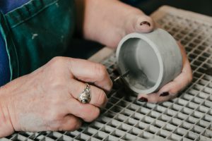 Smoothing the inside of a dish with a scraping tool.