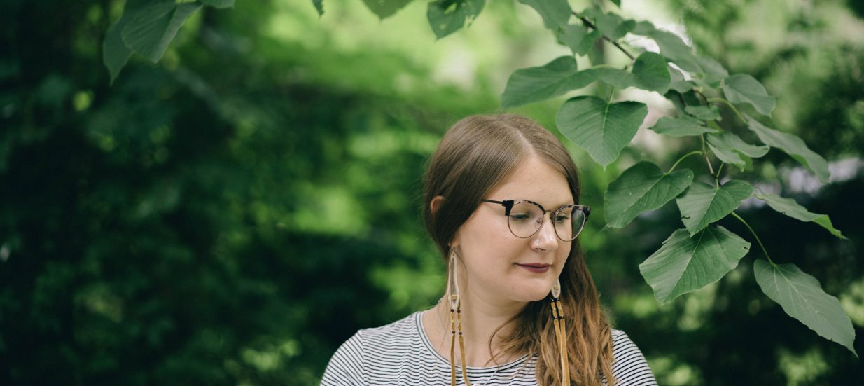 Shelby Lisk standing under a green canopy of leaves and branches.