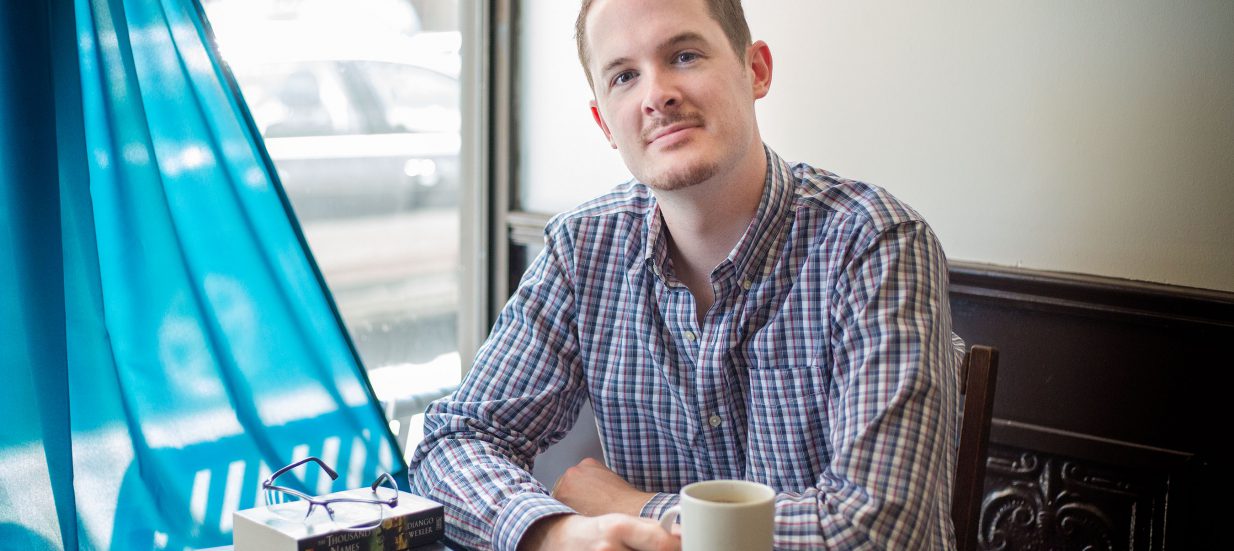 Greg Murphy, of Hero Editorial, sitting at a table with a mug of coffee.