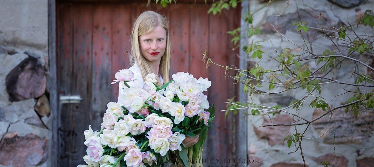 Melanie Harrington holding a bouquet of flowers in front of a barn door.