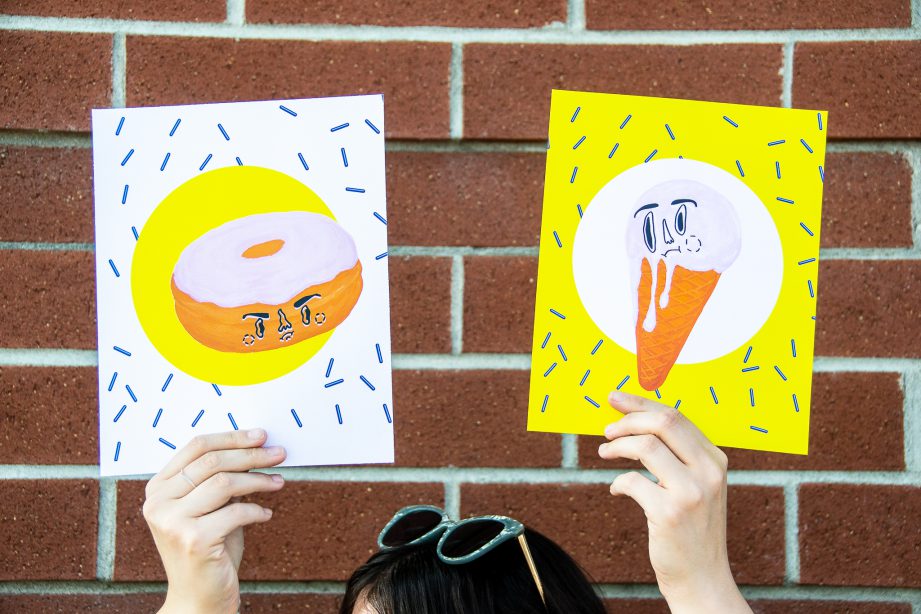 Ashley King holds up two colourful pieces of art  a doughnut and ice cream cone).