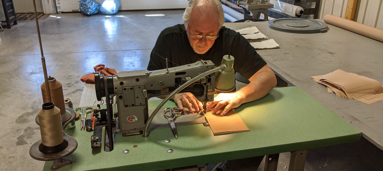 A man sitting behind a table sewing.