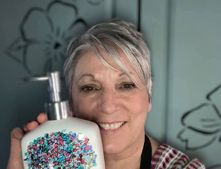 A woman holding a painted soap pump bottle.