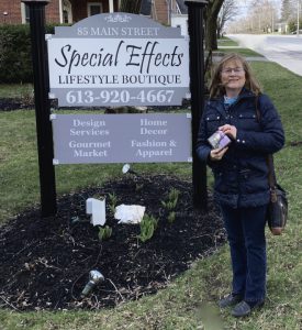 A woman standing next to a sign that says, Special Effects Lifestyle Boutique