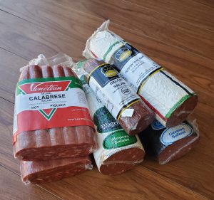 Packages of cured meats stacked on a wooden table.