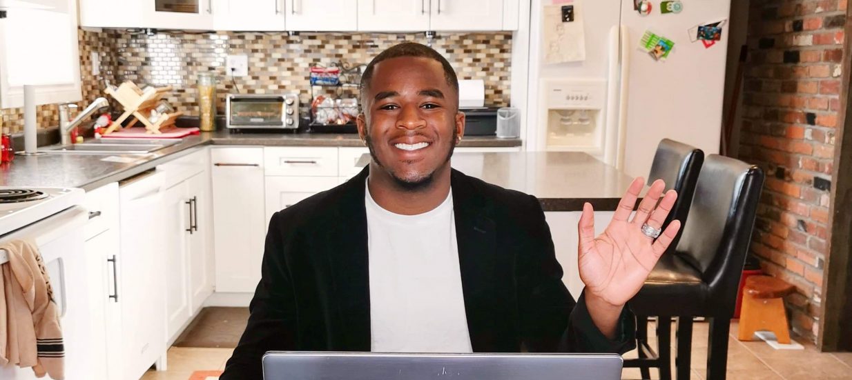 A man sitting at a kitchen table working at a laptop.