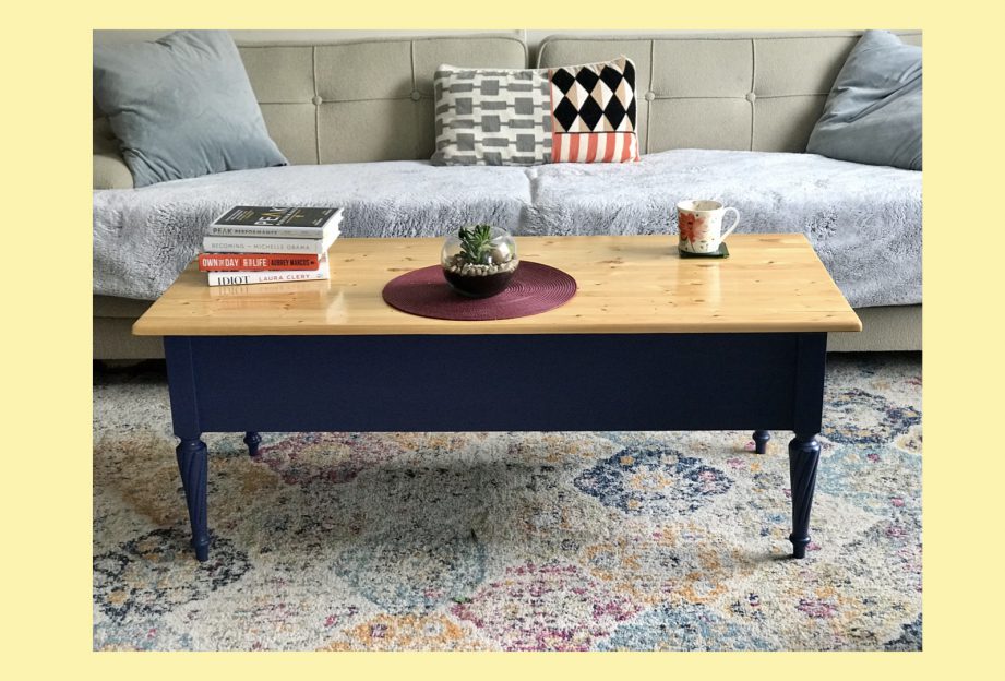 A coffee table on a rug in front of a grey couch.