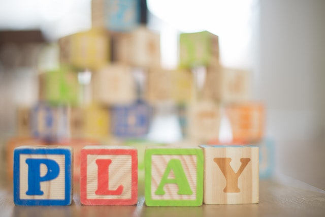 Wooden block letters lined up to spell the word 'play'.