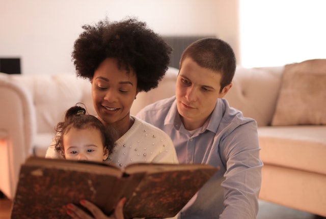 A family of three reading a book together.