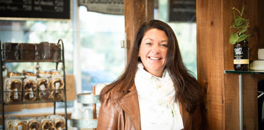 A person wearing a white shirt and brown jacket standing next to a wood beam. Melissa Strecker, owner of Farmer's Daughter Sub Shoppe in Quinte West, shares how the business has been Makin' It Work through COVID-19.