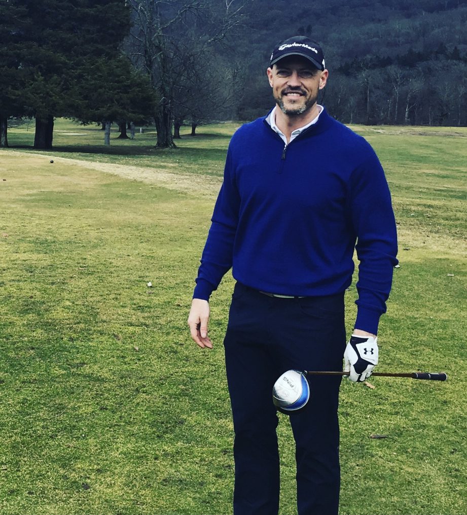 A person standing on a golf course holding a golf club.