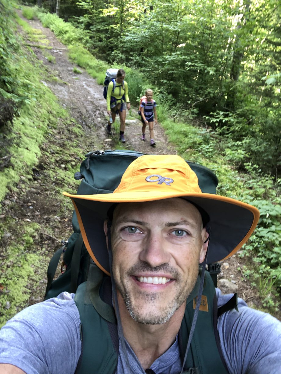 A person wearing a yellow hat standing on a trail.