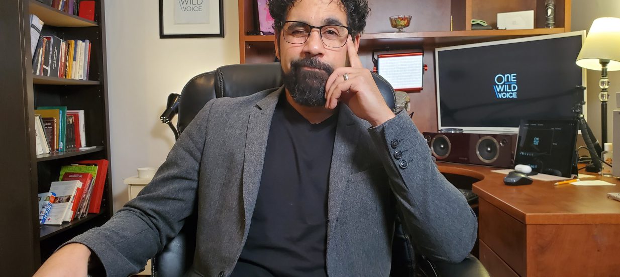 A person in a grey suit sitting in an office chair.