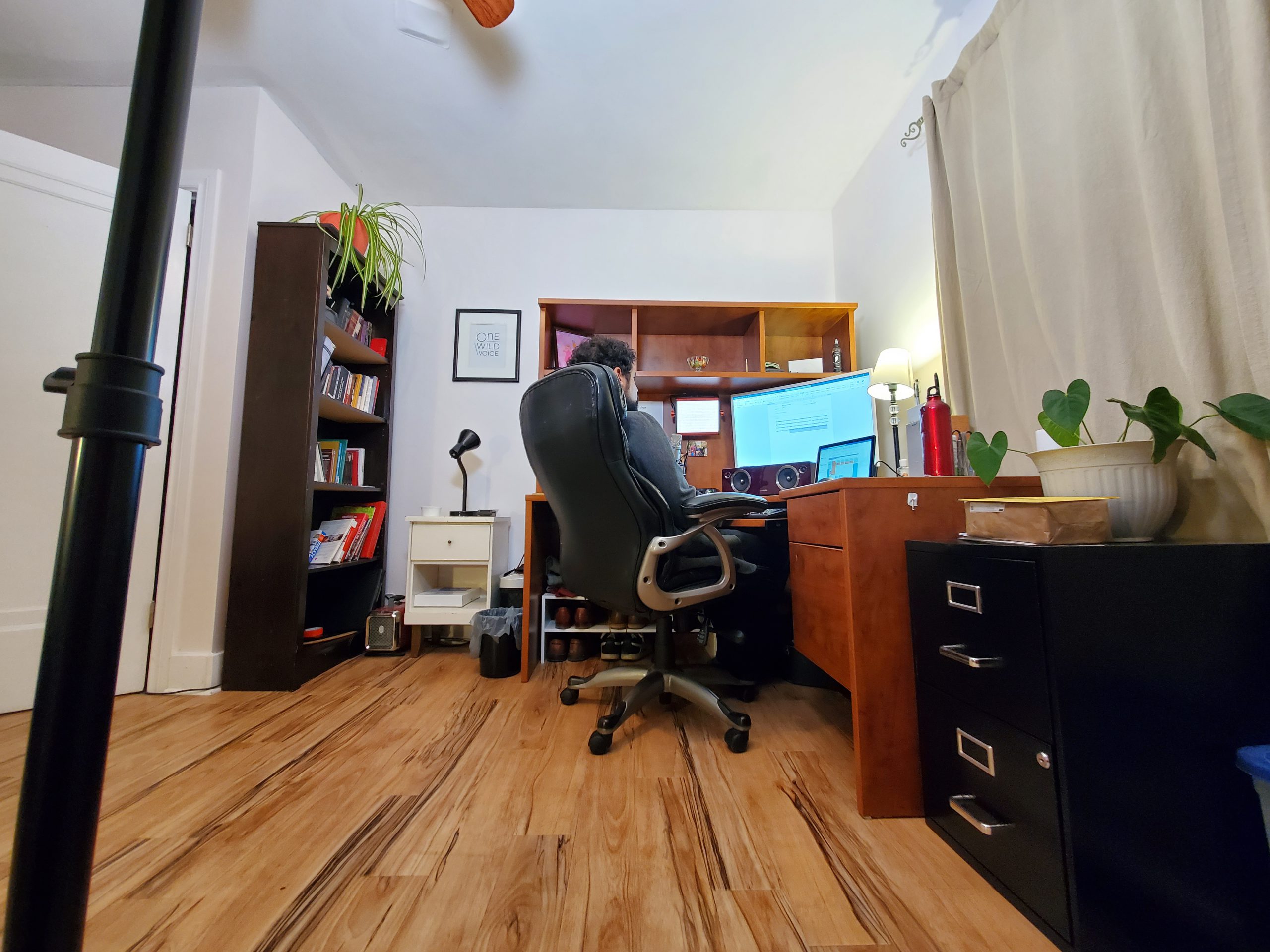 A person sitting in an office chair, with white walls and dark furniture in the office.