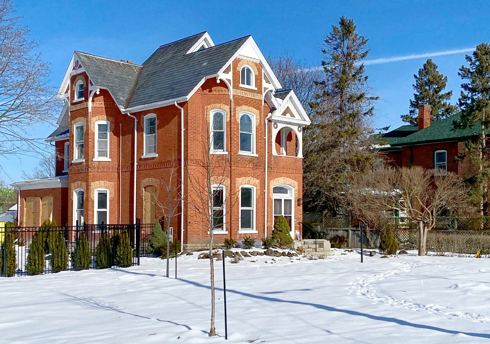 A red brick house with a snow-covered lawn.