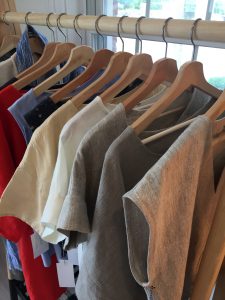 A variety of shirts hanging on wooden hangers.