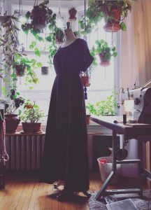 A dark blue dress on a bust in front of a window.