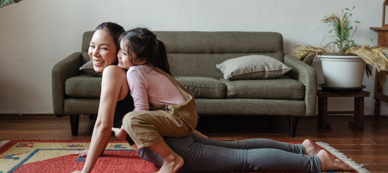 A person doing a yoga pose with a child on their back.