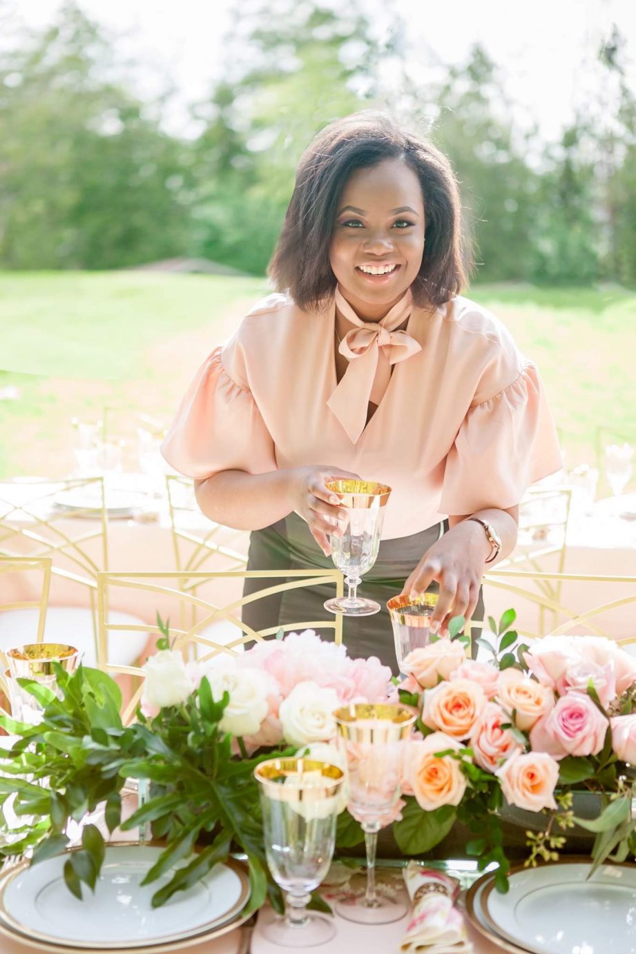 A person standing outside behind a table covered in flowers.