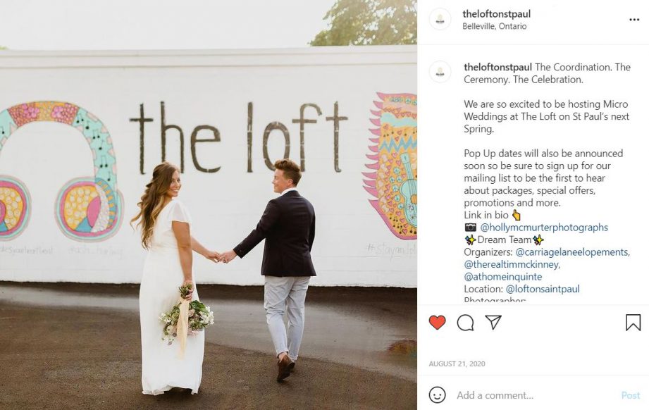 A screenshot of an Instagram photo. Two people dressing in wedding clothes, walking towards a white wall painted with the words, The Loft.