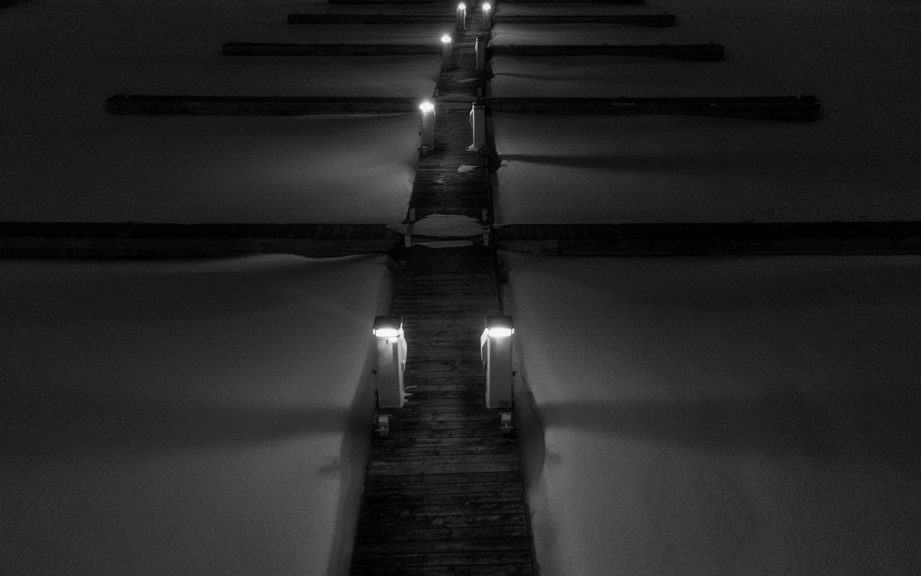 A boardwalk at a pier at night, covered in snow.