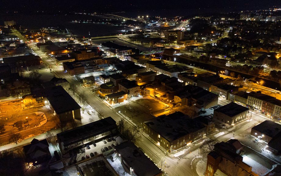 Aerial shot of a city at night with lots of lights on.