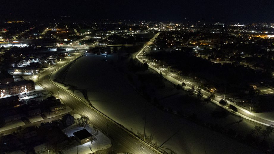 Aerial shot of a river at night with city street lights alongside it.