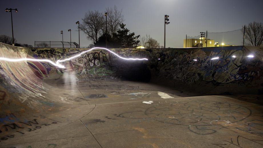 A skate park at night with a light streak around the edge.