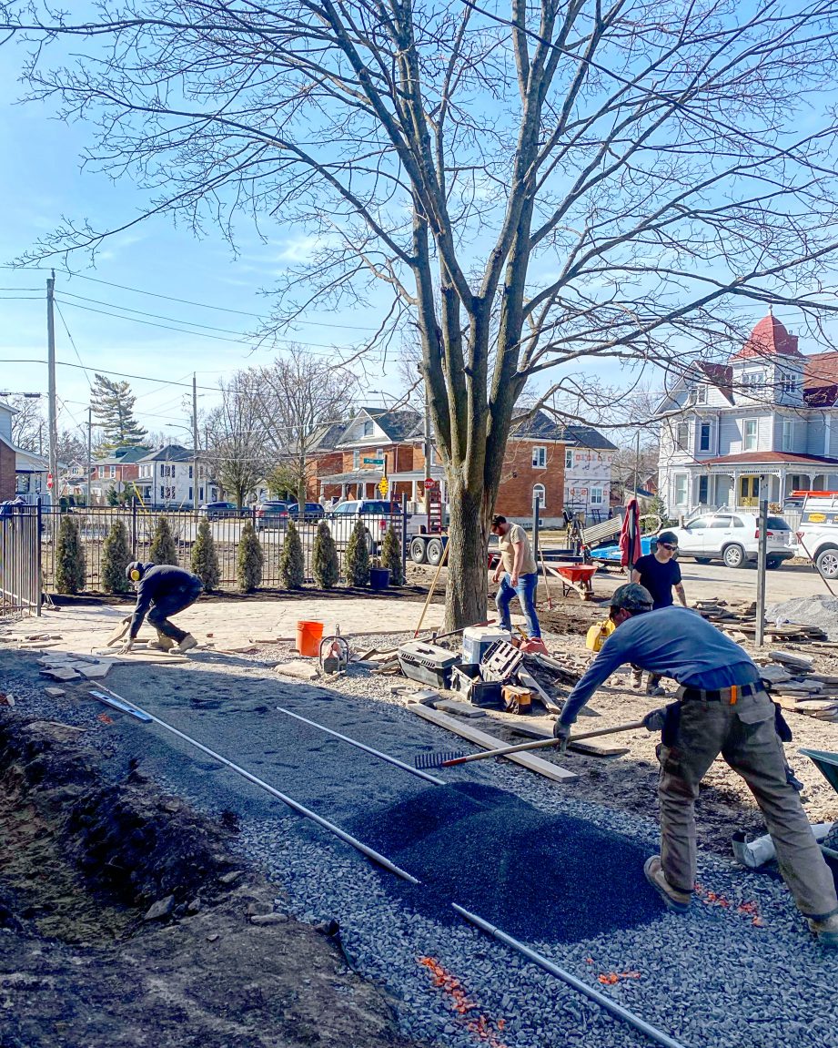 People doing yardwork and raking gravel.