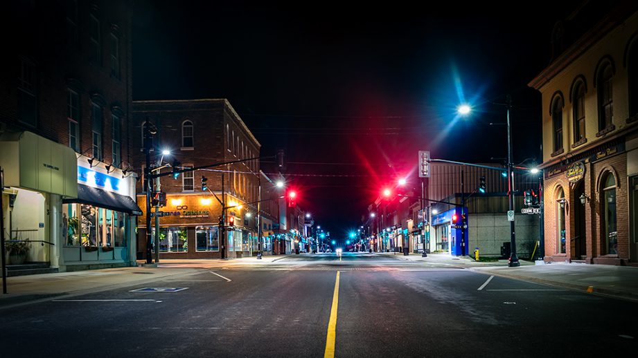 A dark street intersection at night, with bright street lights.