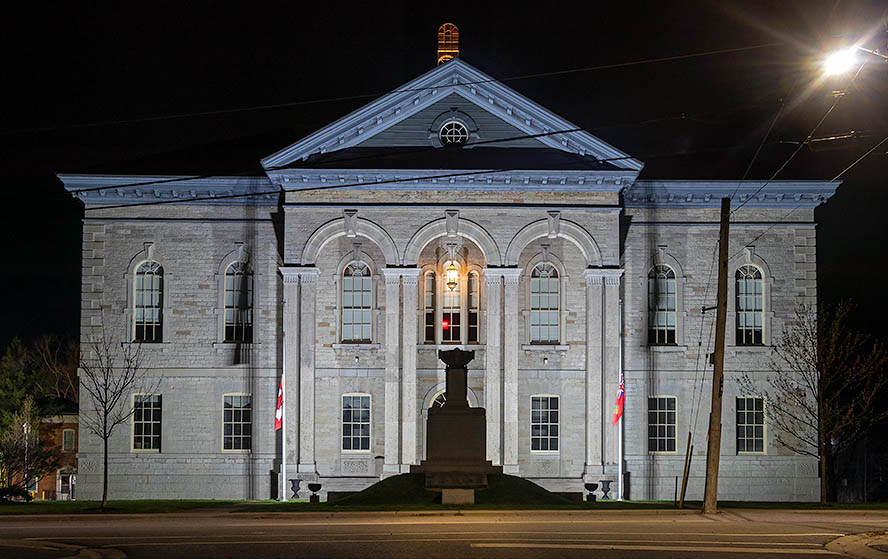 A large white courthouse on a dark evening with a starry sky.