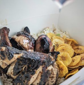 A white takeout container with chicken, plaintains and rice.