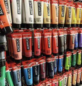 Tubes of paints in all colours on a rack at a craft store.