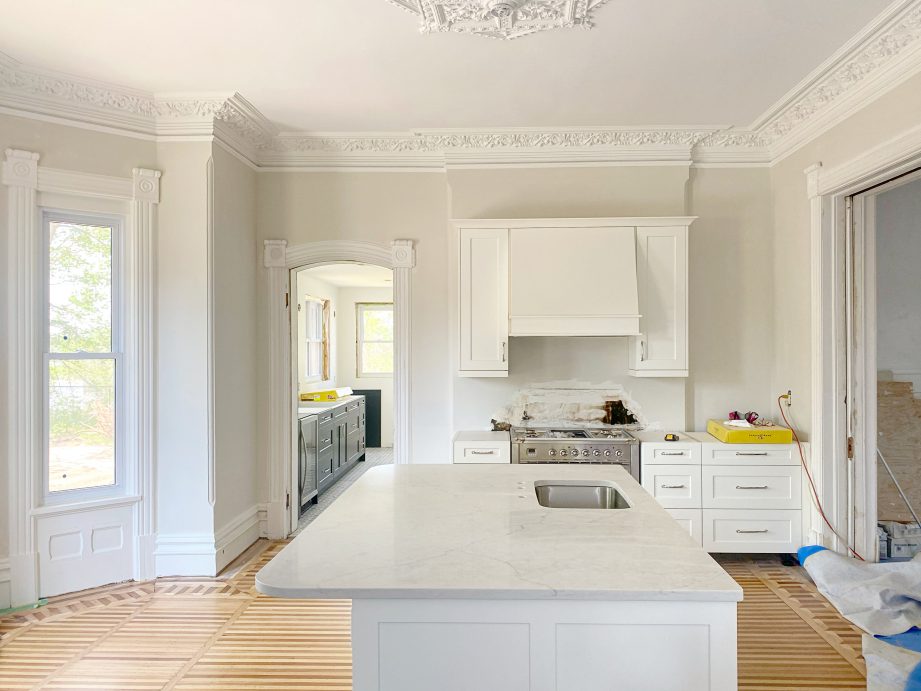 A partially renovated kitchen with wood floors and white fixtures.