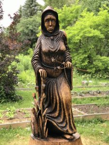 Wooden sculpture of a woman in a cloak done by Daniel Decouvreur, specializing in wood and tree stump sculptures in Quinte West.