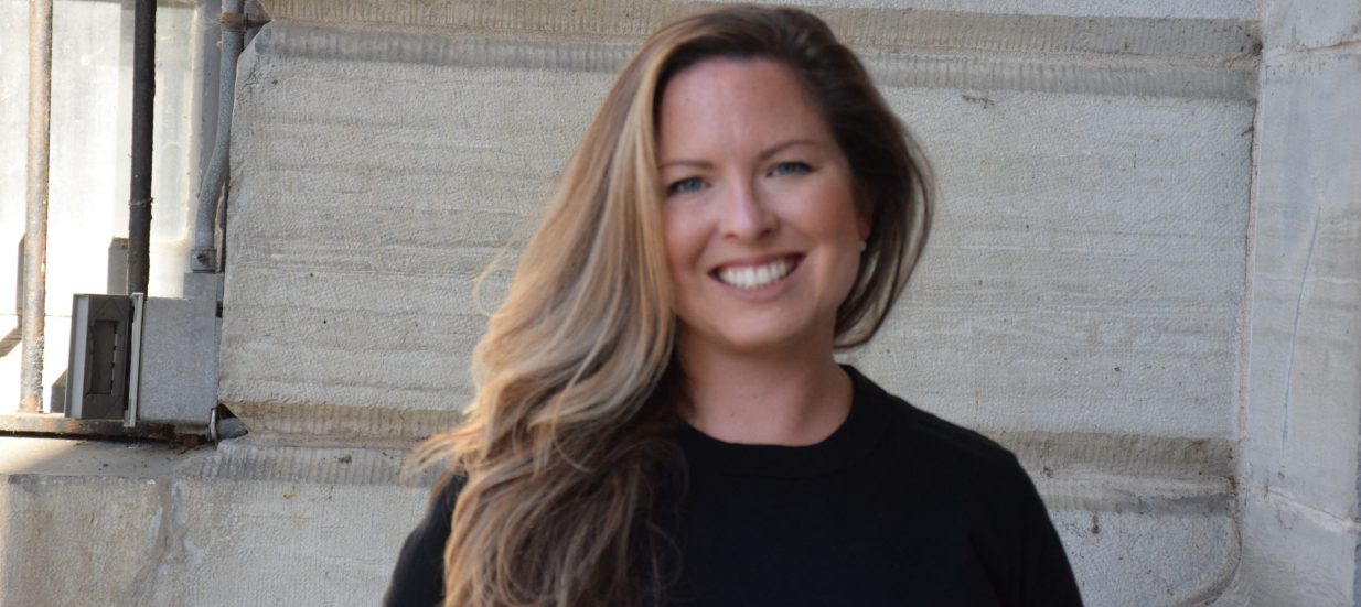 A portrait photo of Shalagh Elliott, woman with long blonde hair smiling at the camera