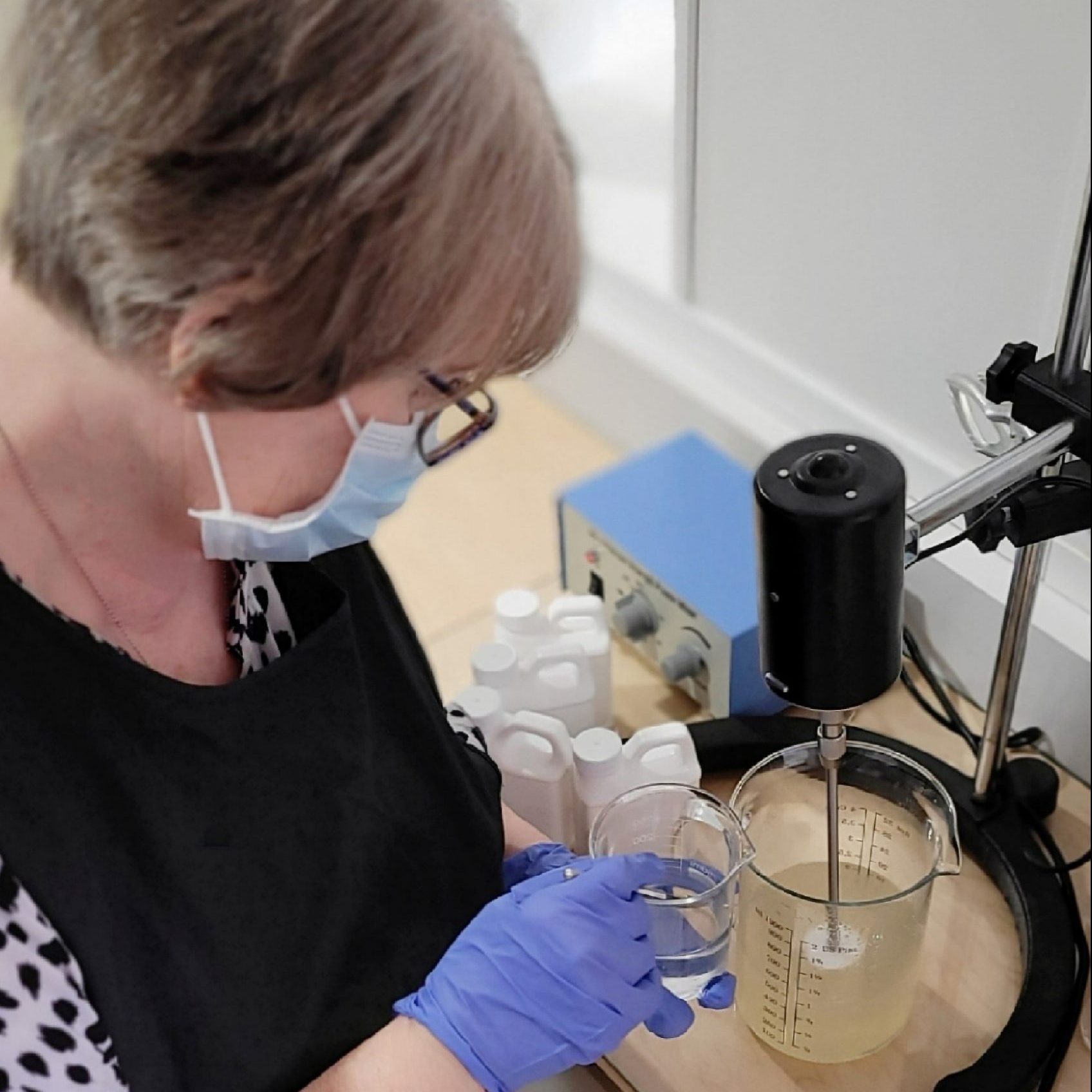 Jacqui of ROCIA Naturals wearing a mask and gloves while mixing ingredients to create her skincare products