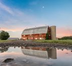 A large, red barn reflecting in the water at Karlo Estates Winery in Prince Edward County.